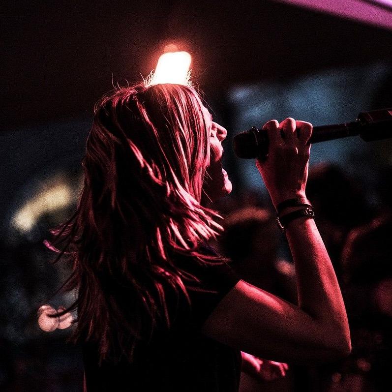 Stephanie beim Singen im Halbdunkel von der Seite gesehen, violette Farben