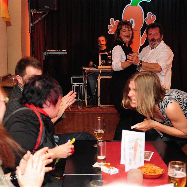 Stephanie singt eine am Tisch sitzende Frau an, die wiederum ebenfalls singt