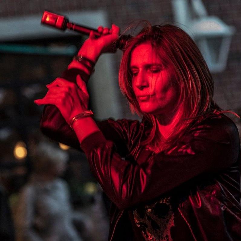 Stephanie beim Singen im Halbdunkel von der Seite gesehen, sie klatscht, rote Farbtöne