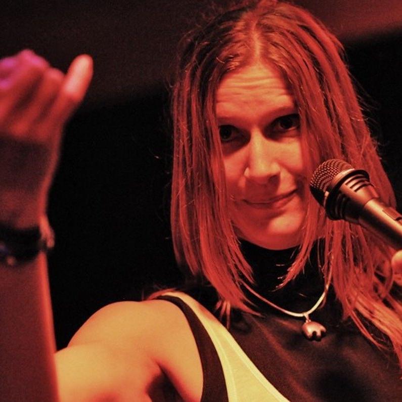 Stephanie beim Singen im Halbdunkel von vorn gesehen, sie macht eine Handgeste