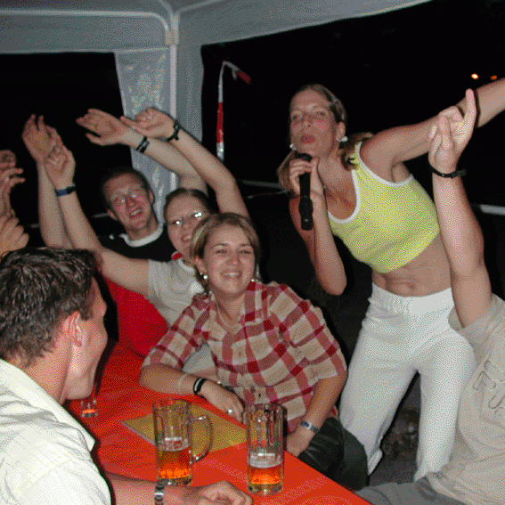 Stephanie zwischen feiernden Gästen, die die Hände nach oben halten und mitsingen